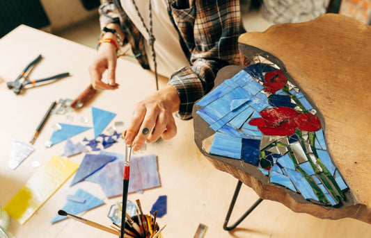 Artist cutting sheets of stained glass into small mosaic art squares