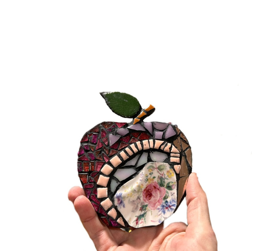 Hand holding mosaic shaped into an apple. Beautiful ceramic and glass mosaics
